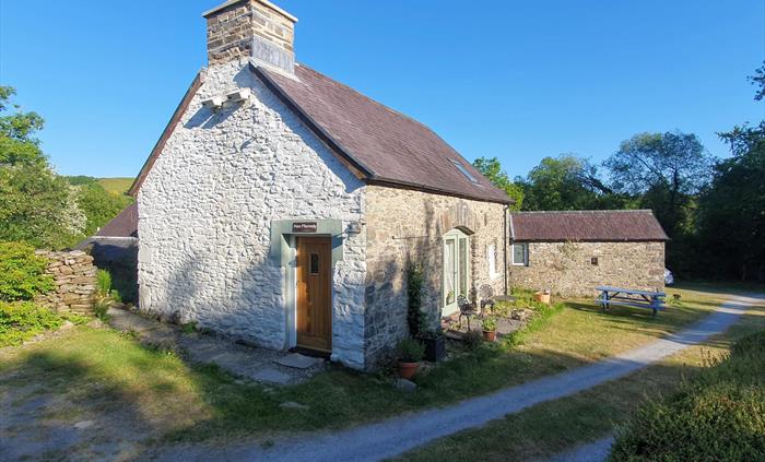 Exterior view of Hen Ffermdy cottage with front small patio with table and chairs